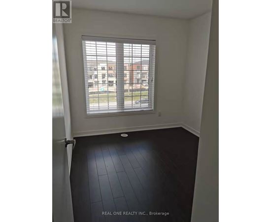 A room with a window and a view of a parking lot and buildings outside.