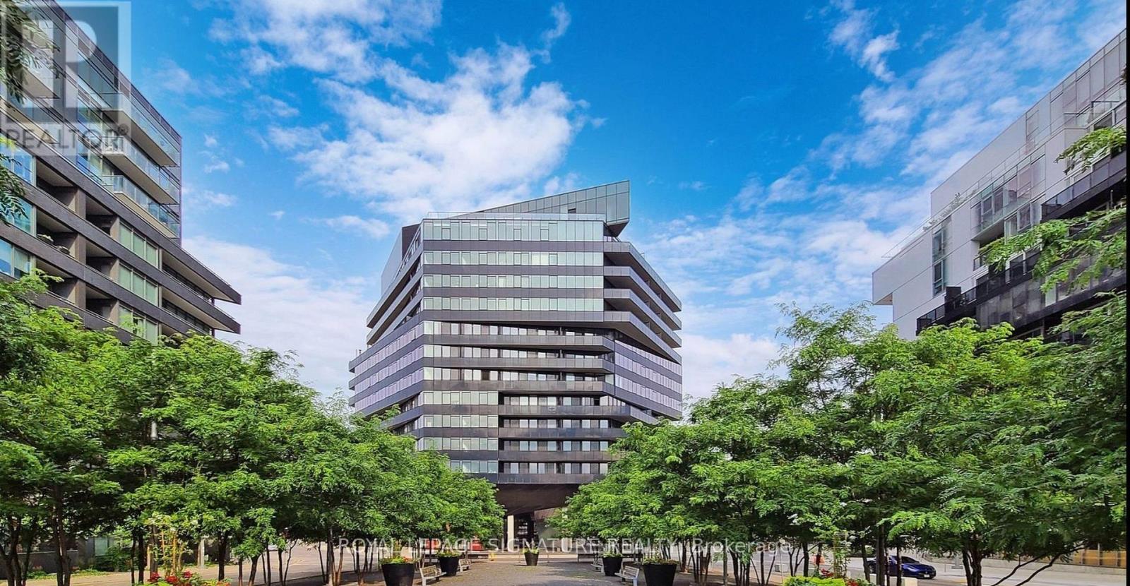 A modern glass building with trees in front of it.