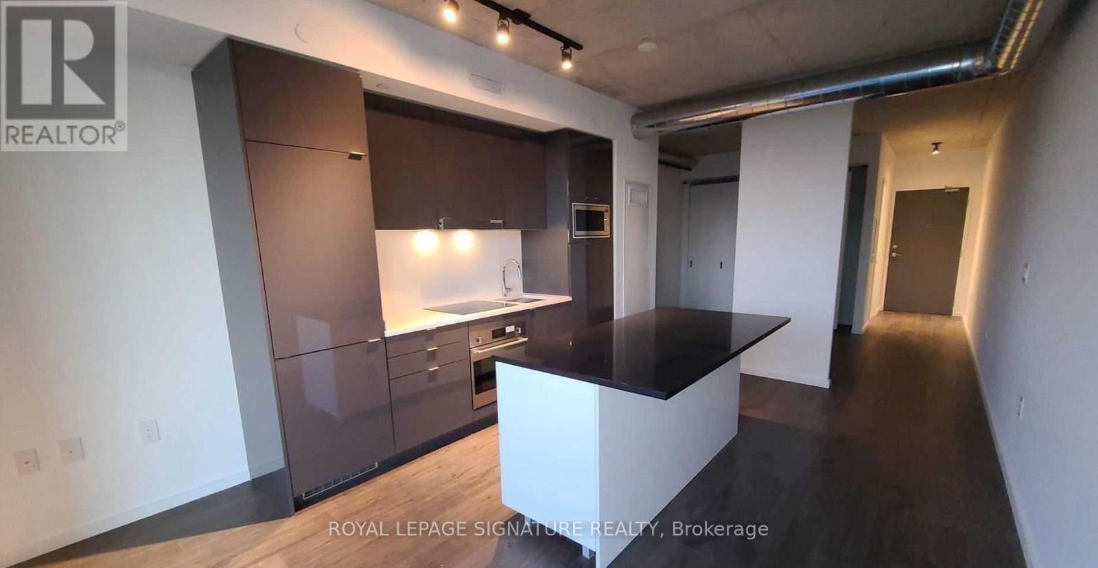 A modern kitchen with dark brown cabinets and a white island.