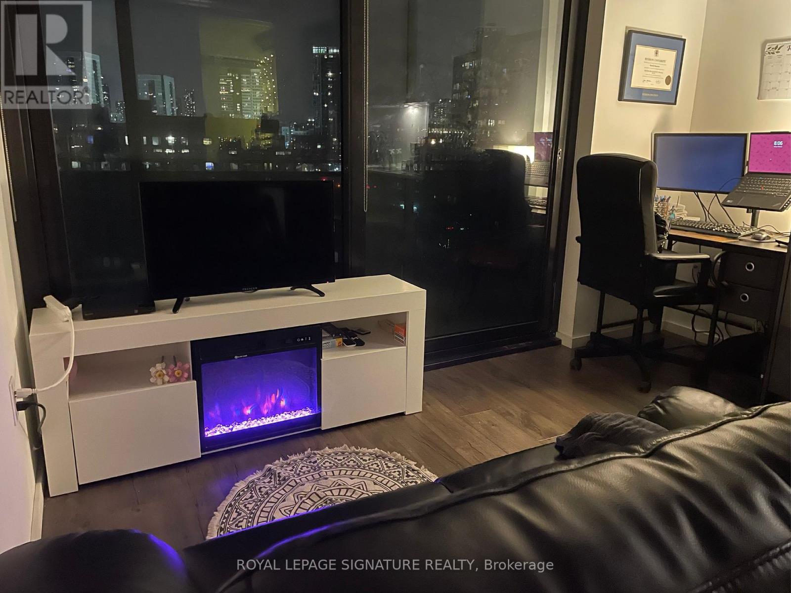 A modern living room with a fireplace and a view of the city at night.