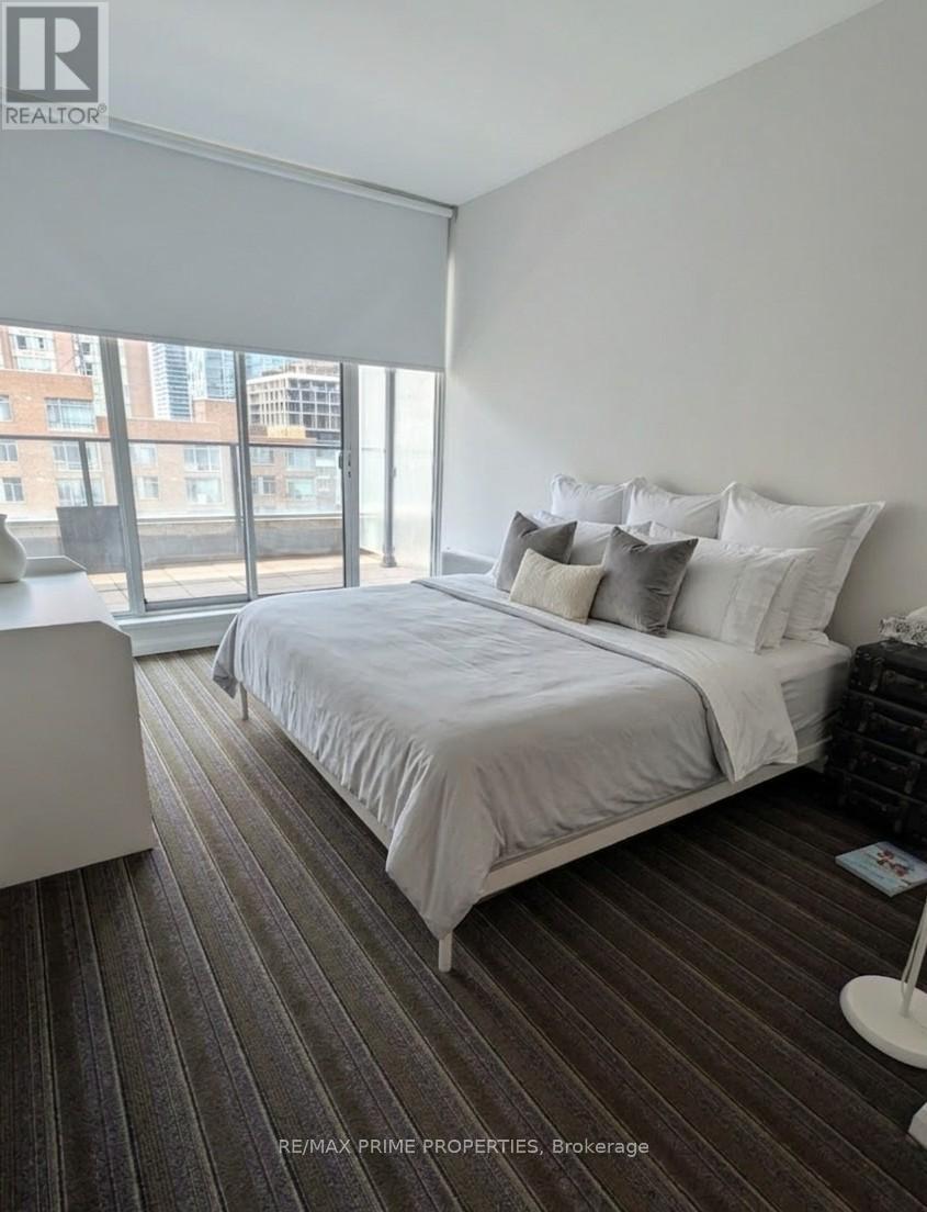A bedroom with a large bed and a window overlooking a cityscape.