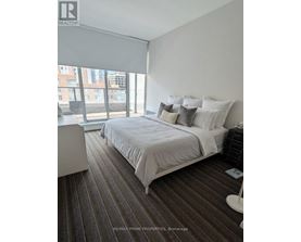 A bedroom with a large bed and a window overlooking a cityscape.