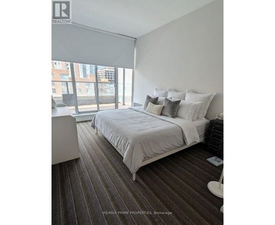 A bedroom with a large bed and a window overlooking a cityscape.