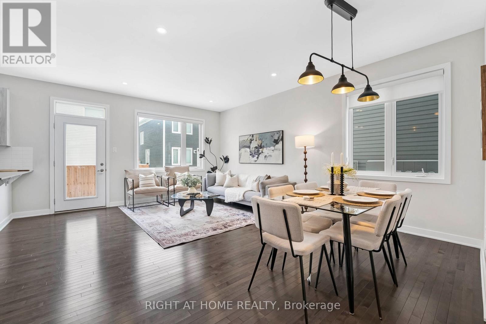 A dining room with a table set for six with a view of the kitchen.