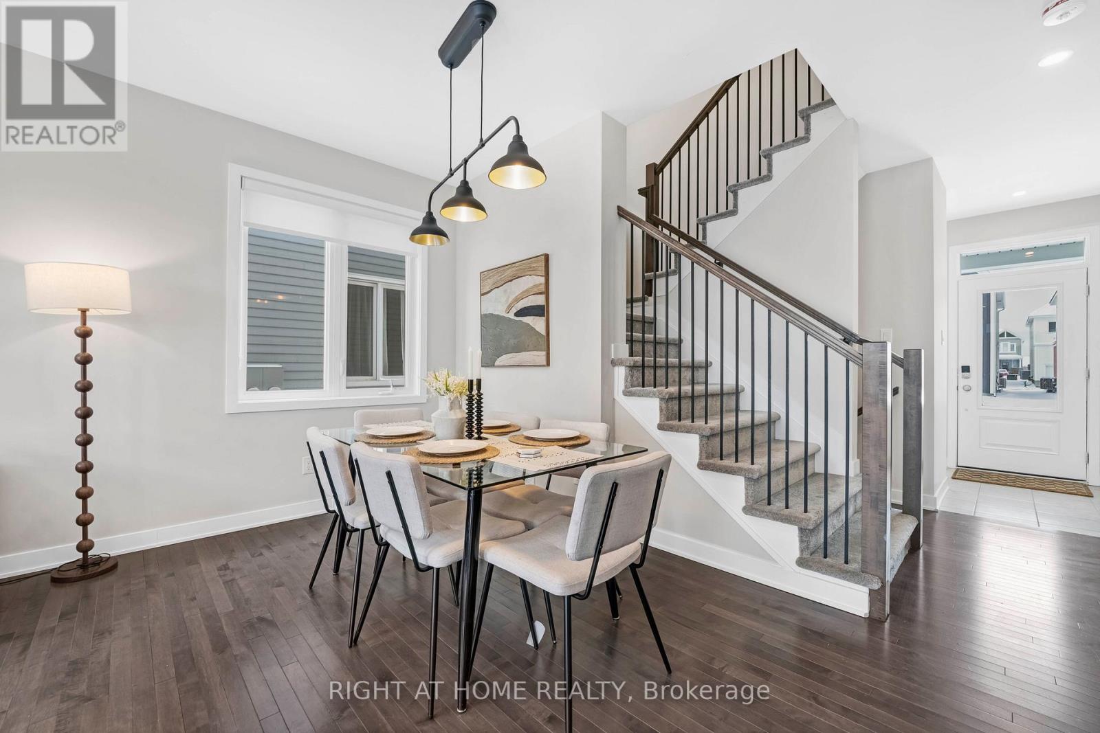 A dining room with a table set for four and a staircase in the background.