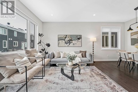 A well-lit living room with a large window, a sofa set, a coffee table, and a rug.