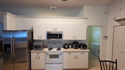 A kitchen with white cabinets and appliances.