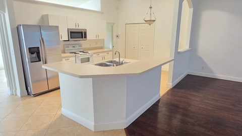 A kitchen with a refrigerator, microwave, and sink.