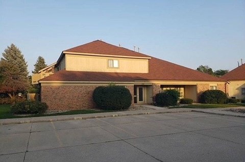 A house with a brown roof and a driveway in front.