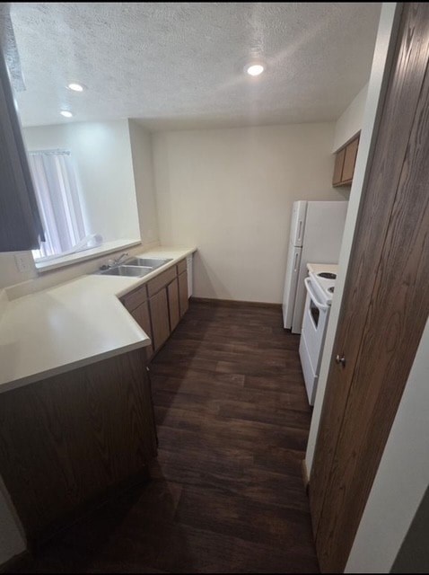 A kitchen with a white fridge and wooden floors.