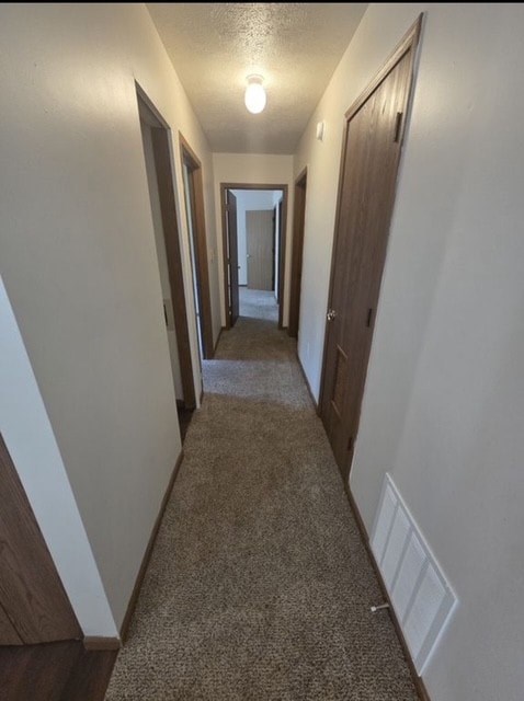 A hallway with a carpeted floor and white walls.