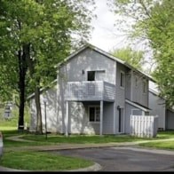 A grey house with a white fence in front.