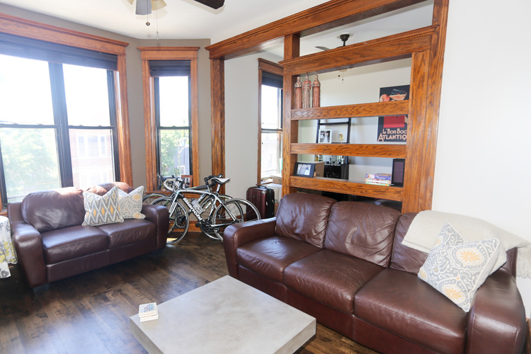 A living room with brown leather couches and a bicycle in the corner.