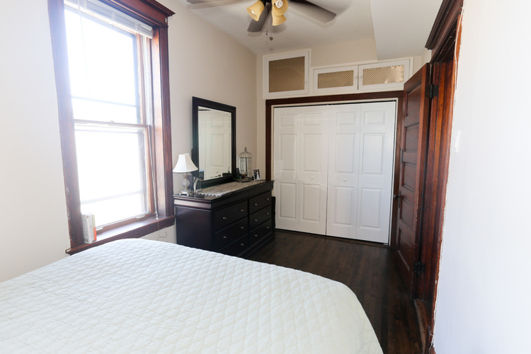 A bedroom with a bed, dresser, and mirror.