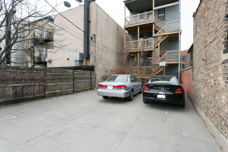 Two cars parked in a narrow alley between buildings.