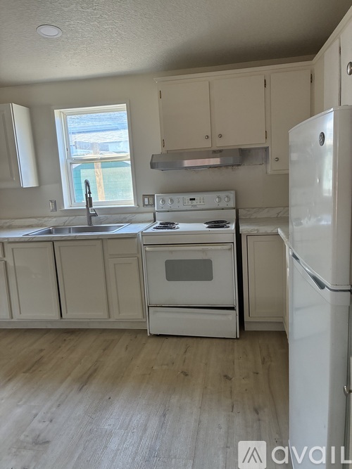 A kitchen with white appliances and wooden floors.