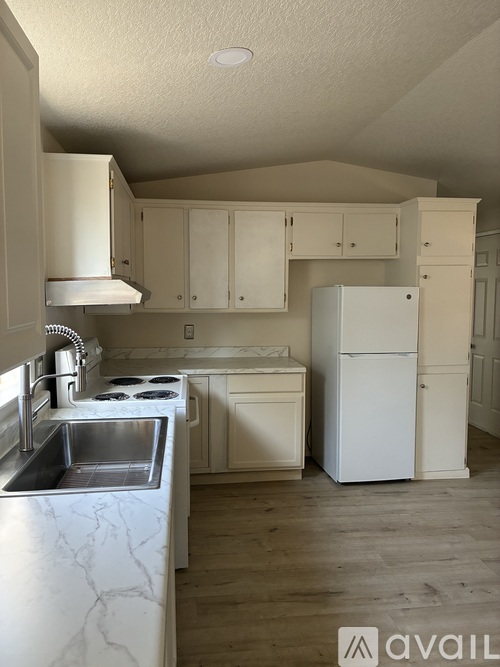 A kitchen with white cabinets and a white refrigerator.