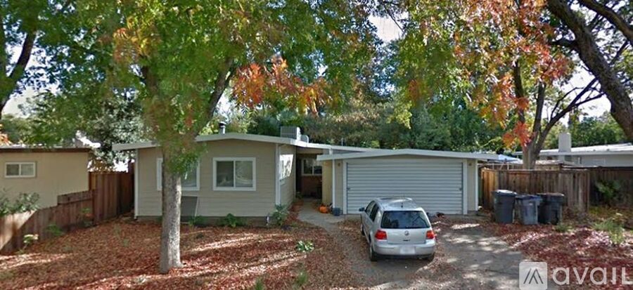 A tree with orange leaves is in front of a house with a garage.