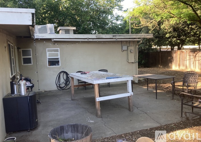 A patio with a table and chairs is surrounded by a fence and trees.