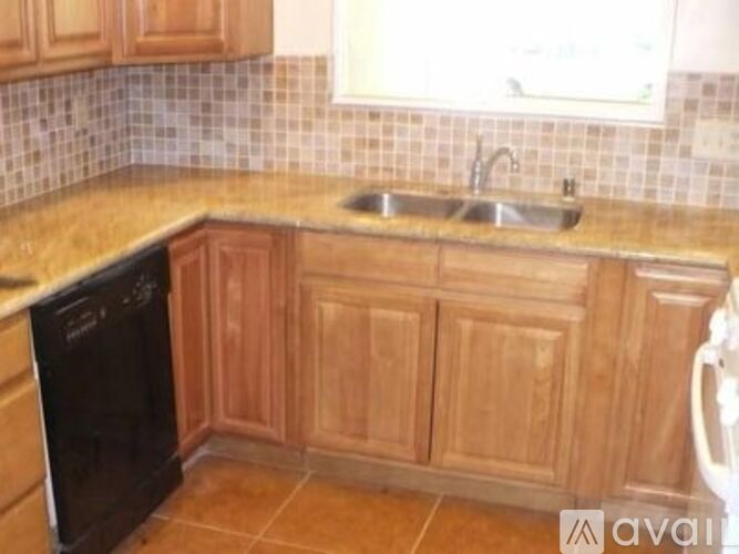 A kitchen with wooden cabinets and a black dishwasher.