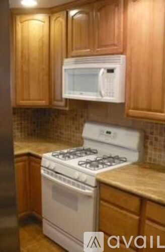 A white stove and microwave in a kitchen with wooden cabinets.