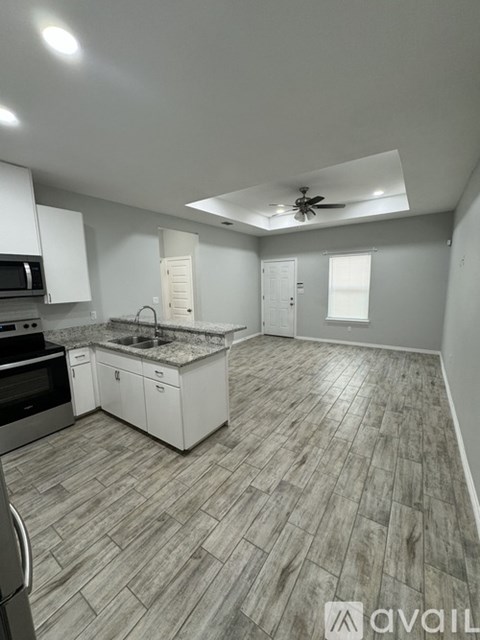 A kitchen with a wooden floor and white cabinets.