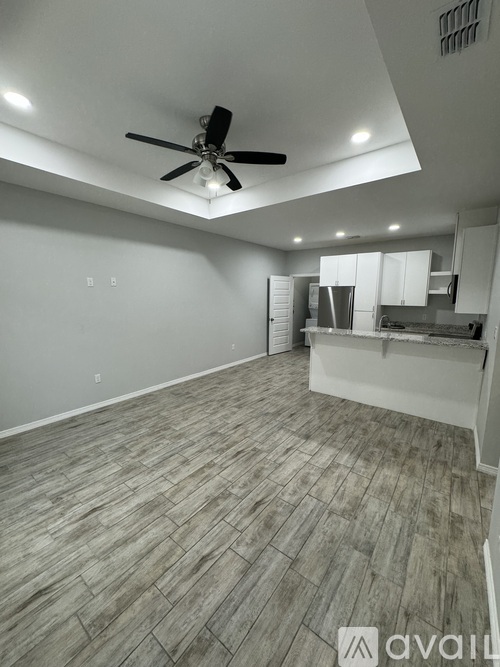 A spacious room with a ceiling fan and wooden flooring.