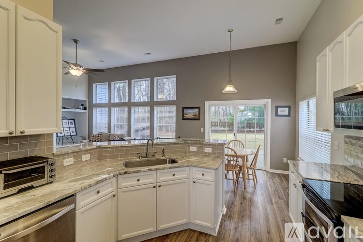 A kitchen with white cabinets and a wooden floor.