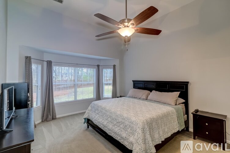 A bedroom with a large bed, a ceiling fan, and a television.