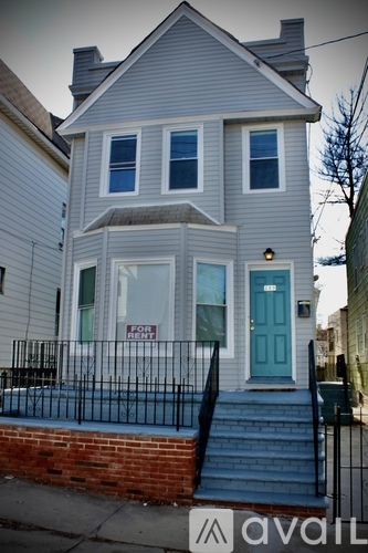 A two-story house with a blue door is for rent.