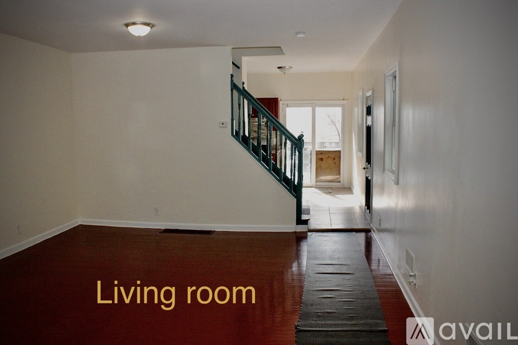 A living room with a wooden floor and a staircase.