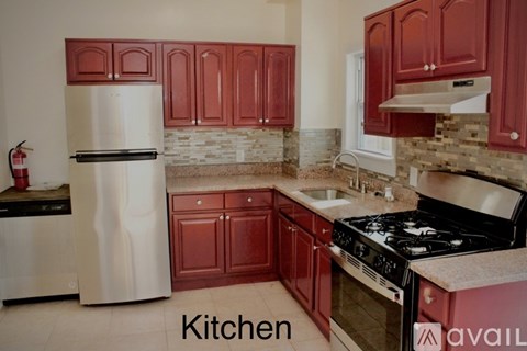 A kitchen with red cabinets and a white refrigerator.