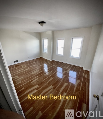 A master bedroom with wooden floors and white walls.