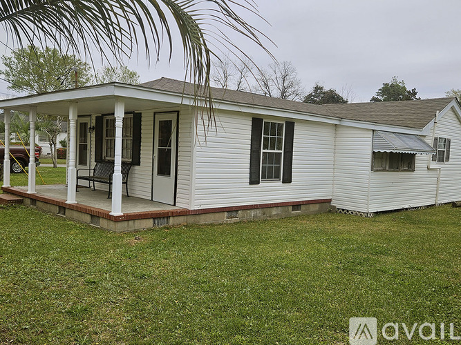 A white house with a porch and a palm tree in the background.