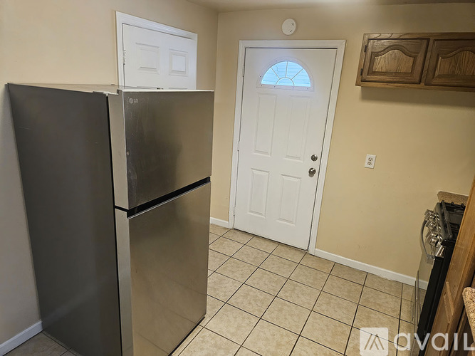 A black refrigerator is in a kitchen with a white door.