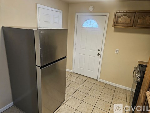 A black refrigerator is in a kitchen with a white door.