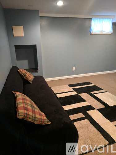 A black couch with a plaid pillow sits in a room with a television.