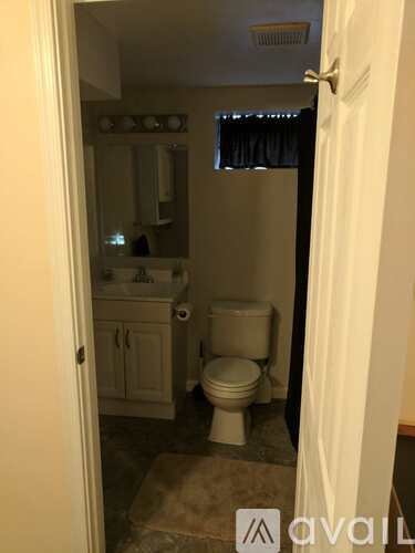 A bathroom with a toilet, sink, and mirror.