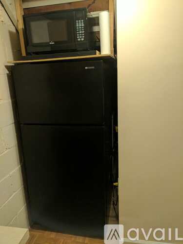 A black fridge with a microwave on top.