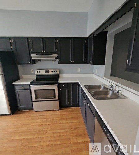 A kitchen with black cabinets and a white fridge.