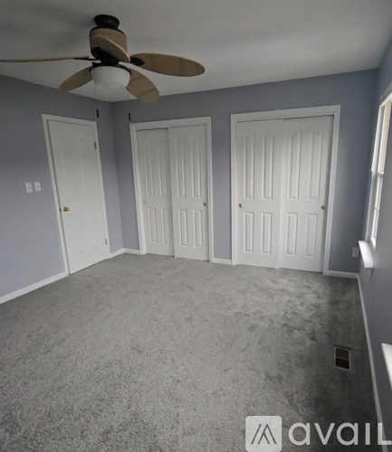 A room with a ceiling fan and three doors.