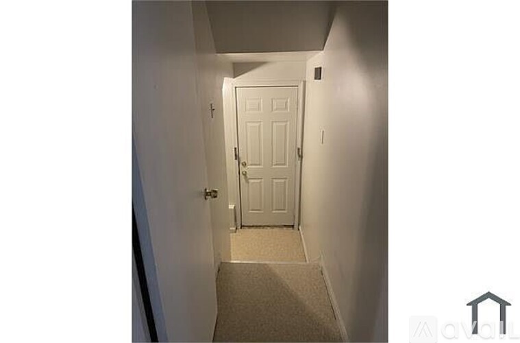 A hallway with a white door and a carpeted floor.