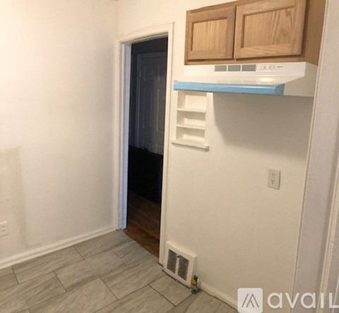 A kitchen area with a white wall and a wooden cabinet.