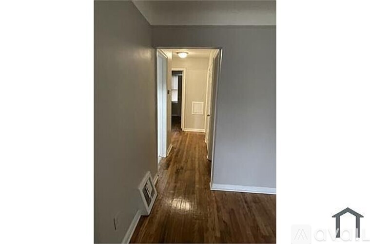 A long hallway with wood floors and white walls.