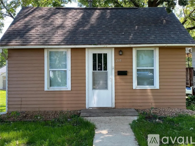 A small brown house with a white door and windows.