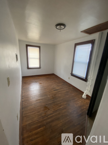 A room with wooden floors and two windows.
