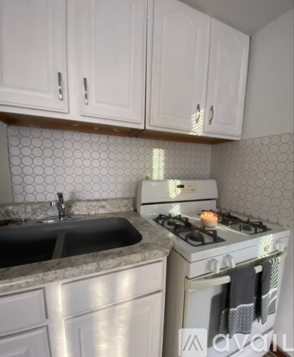 A kitchen with a stove, sink, and cabinets.