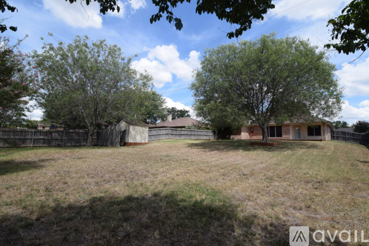 A grassy field with a house and trees in the background.