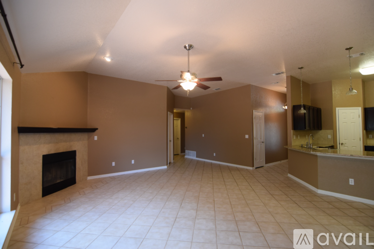 A spacious living room with a fireplace and a ceiling fan.