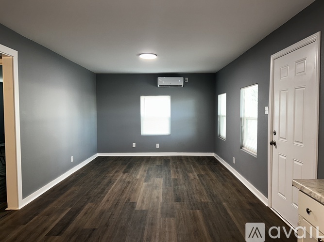 A spacious room with wooden flooring and a white door.